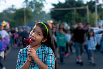 Happy girl eating caramel apple at a fair.