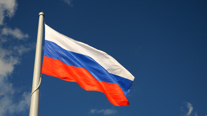 The flag of Russia develops on a flagpole in the wind in the sky