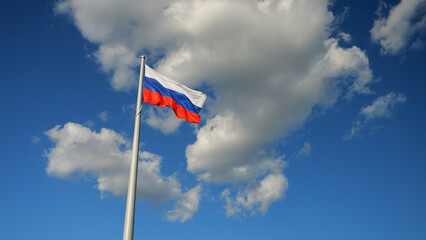 The flag of Russia develops on a flagpole in the wind in the sky