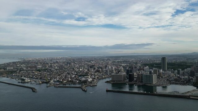 Flying over water towards harbor entrance and central Akashi City