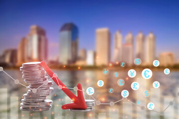 Arrow downwards with coins and decline graph currency symbol on business buildings background. Economic recession concept and revolution real estate industry crisis idea