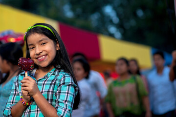 A happy girl holding a caramel apple at a fair.
