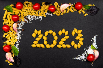 Four types of pasta with garlic, pepper, tomatoes,salt and the numbers 2023 from pasta. Flatlay. Top view. Food. Concept photo. Cooking. New Year.