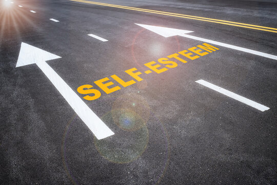 Self-esteem and arrow sign marking on road surface for giving directions. Boosting self esteem concept and improvement idea