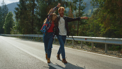 Fototapeta premium Hipsters hiking having fun on mountains hitchhike. Tourists walking highway road