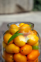 Fresh organic yellow tomatoes in a jar. Organic non-GMO yellow tomatoes on a canning table. The concept of health, non-GMO products, clean ecological food.