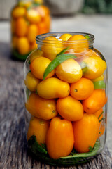 Fresh organic yellow tomatoes in a jar. Organic non-GMO yellow tomatoes on a canning table. The concept of health, non-GMO products, clean ecological food.