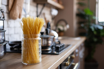 The photo shows pasta in a jar, which stands on the kitchen table. Great background for culinary recipes.