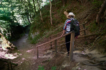 Obraz premium Middle-aged woman with hat and backpack walking