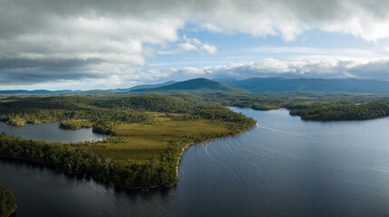 Aerial top down footage of a windy river, in the Tasmania wilderness. Lake with a Sandy beach and trees in Australia