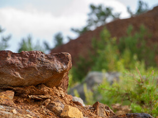 Stone in focus with mountain of slag from Falun Copper Mine World Heritage in background