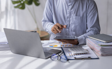 Businessman working at office with calculator documents on his desk, doing planning analyzing the financial report, business plan investment, finance analysis concept	