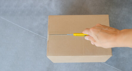 Box on the floor of the store, hand opening with a cutter