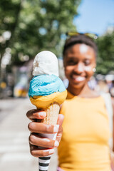 close up of a colorful ice-cream cone on the hands of an unrecognizable african woman