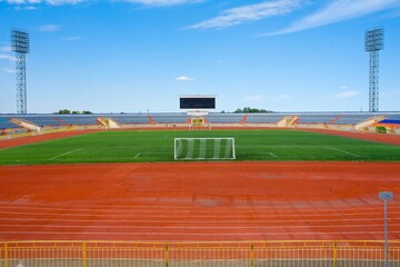 Fototapeta premium STADIUM - Football field with goal and tablo on blue sky