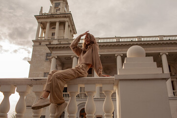 portrait of a style woman walking, enjoys a wonderful atmosphere of a vacation in fall time. The girl is wearing a urban beige sweater,  