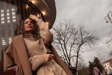 portrait of a style woman walking, enjoys a wonderful atmosphere of a vacation in fall time. The girl is wearing a urban beige sweater,  