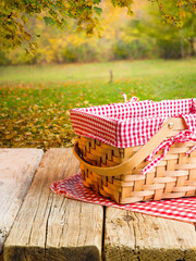 Autumn outdoor recreation, picnic. On a simple wooden table on a checkered napkin, a straw picnic basket against the backdrop of stunning autumn nature. Family traditions, thanksgiving day. - 521497307