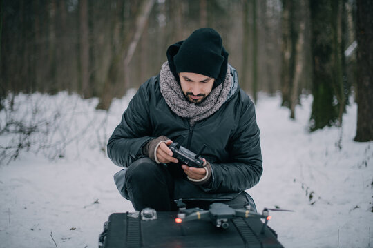 Aerial photography specialist with a copter in his hands on the street in winter. A male aerial drone operator at work on a film set for a movie