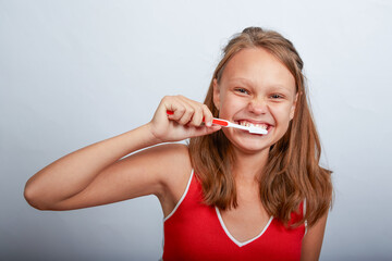 a beautiful girl of 11 years old brushes her teeth on a white background