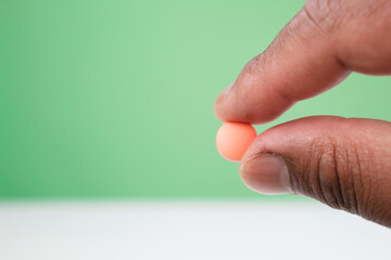 Dietary supplement, afro man hand, Nutrition diet healthy eating, beauty people. Male hand holding a capsule, pill or vitamin. isolated green background