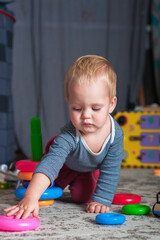 Toddler boy plays with plastic pyramid in playroom..