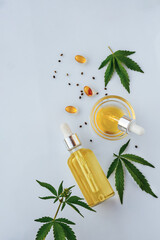 CBD oil in bottle with pipette, capsules, marijuana leaves on white background