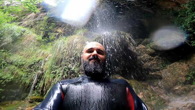 Hombre con traje de neopreno debajo de una cascada concepto de aventura y exploracion