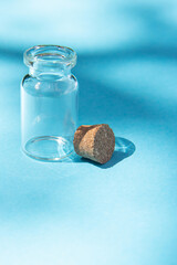 Modern apothecary concept. Open empty glass miniature bottle with cork cap on a blue background. Still life compositions