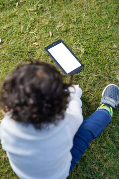 Indian little boy sitting with laptop and tablet in the garden