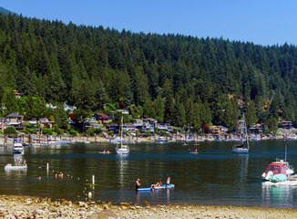 Leisure craft moored near swimmers at a scenic BC beach popular with kayakers and paddlers of all sorts.