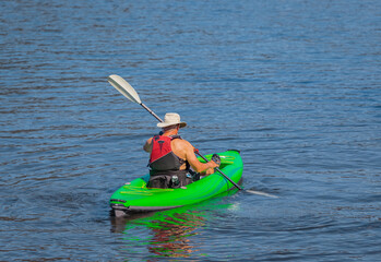 Senior man practicing kayaking. Summer landscape, a man fisherman floats on an inflatable boat on the Cultus lake