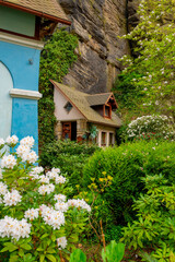 house fragment built into the rock with beautiful flowers. Hrensko, Czech republic