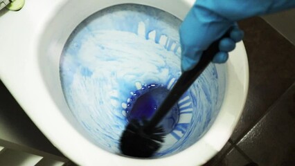 gloved hands cleaning the toilet