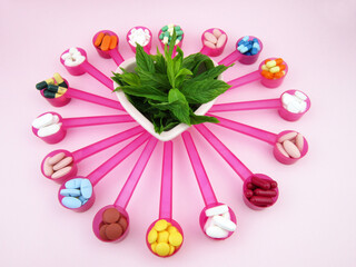       pills, tablets, capsules in pink spoons and plant inside heart in center            