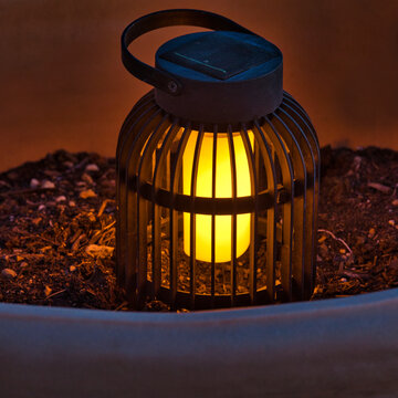 Garden Light. Isolated.Decorative solar lantern in garden pot resting on soil creating a soft moody atmosphere at night. Stock Image.