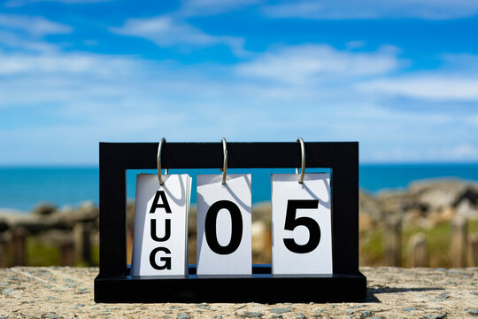 August 5 calendar date text on wooden frame with blurred background of ocean.