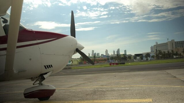 Tilt-Up Pan Of A Cessna 172 High Wing Aircraft Parked At Airport With City In Background - Panama City, Panama