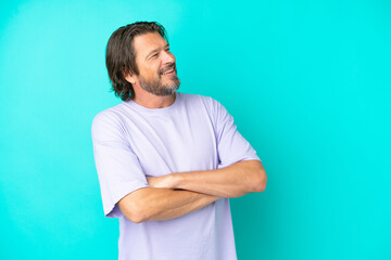 Senior dutch man isolated on blue background happy and smiling