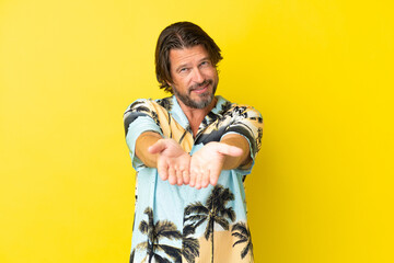 Senior dutch man isolated on yellow background holding copyspace imaginary on the palm to insert an ad