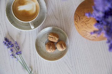  Vegan natural nuts sweets with no sugar. Cup of cappuccino on wooden table in the cafe. Natural sweets. Coffee break. Lavender decorations.