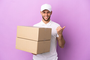 Delivery caucasian man isolated on purple background pointing to the side to present a product