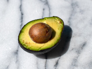 avocado cut in half on a marble background 