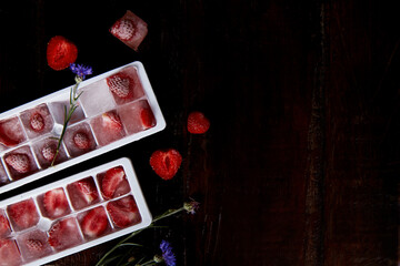 Strawberry ice in the forms. Preparing summer ice for party cocktails, ice-cream and desserts. Freshness. Copy space