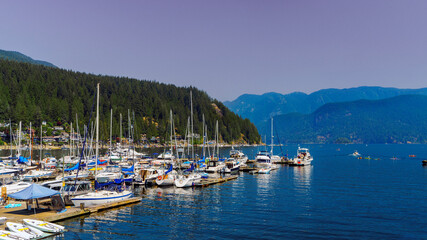Fototapeta na wymiar Spectacular mountain backdrop to Burrard Inlet mooring at beautiful Deep Cove, BC, on a mid-summer day.