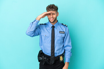 Fototapeta premium Young police blonde man isolated white on blue background looking far away with hand to look something