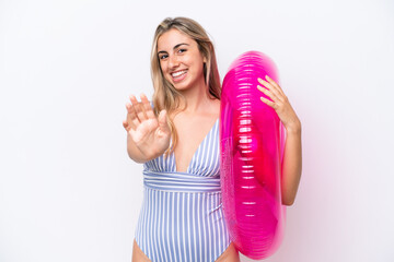 Young caucasian woman holding air mattress donut isolated on white background saluting with hand...