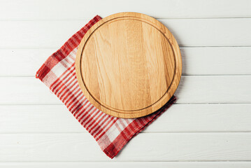 Round wooden cutting board with a napkin on a wooden table.