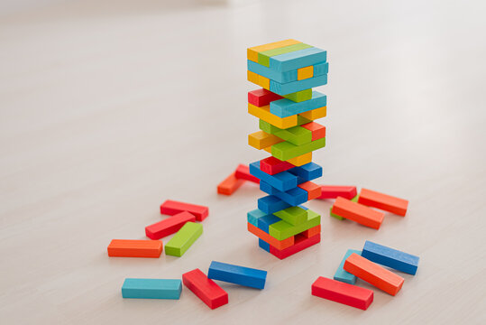Board game Jenga Tower made of wooden blocks. A tower of unevenly shifted wooden beams. A lesson for agility, logic and coordination. Home entertainment. Balance.
