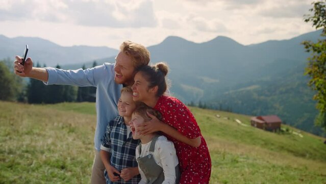 Funny family fooling making selfie on mountains. Parents taking photo with kids